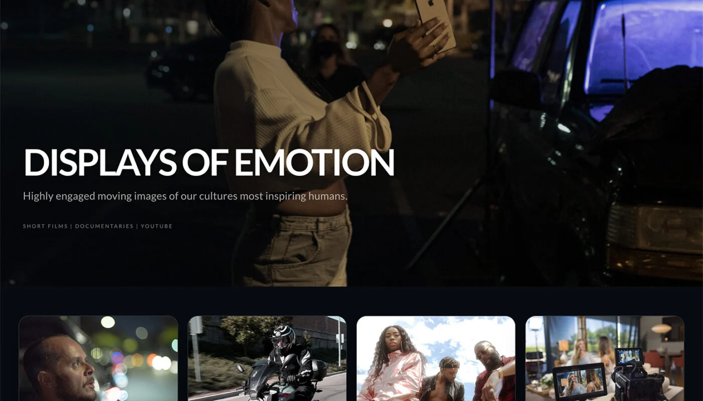 Nighttime hero image of a person holding a smartphone up to take a photo of a blue-lit car, city lights in the background, with bold title text 'DISPLAYS OF EMOTION' overlaid.
